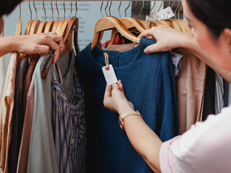 Frau betrachtet Preisschild am Textilienstand