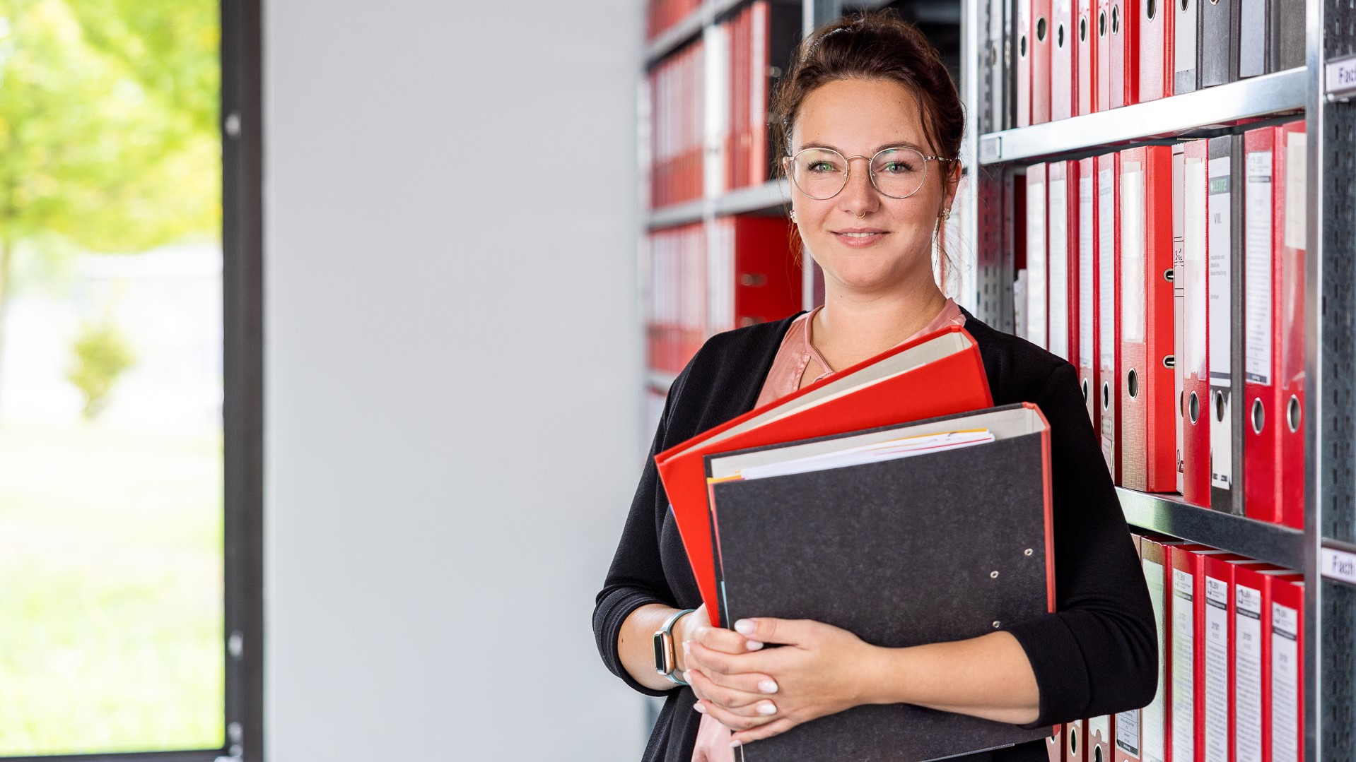 junge Frau steht mit Akten in der Hand vor einem Aktenschrank (© LBV/Julia Otto)