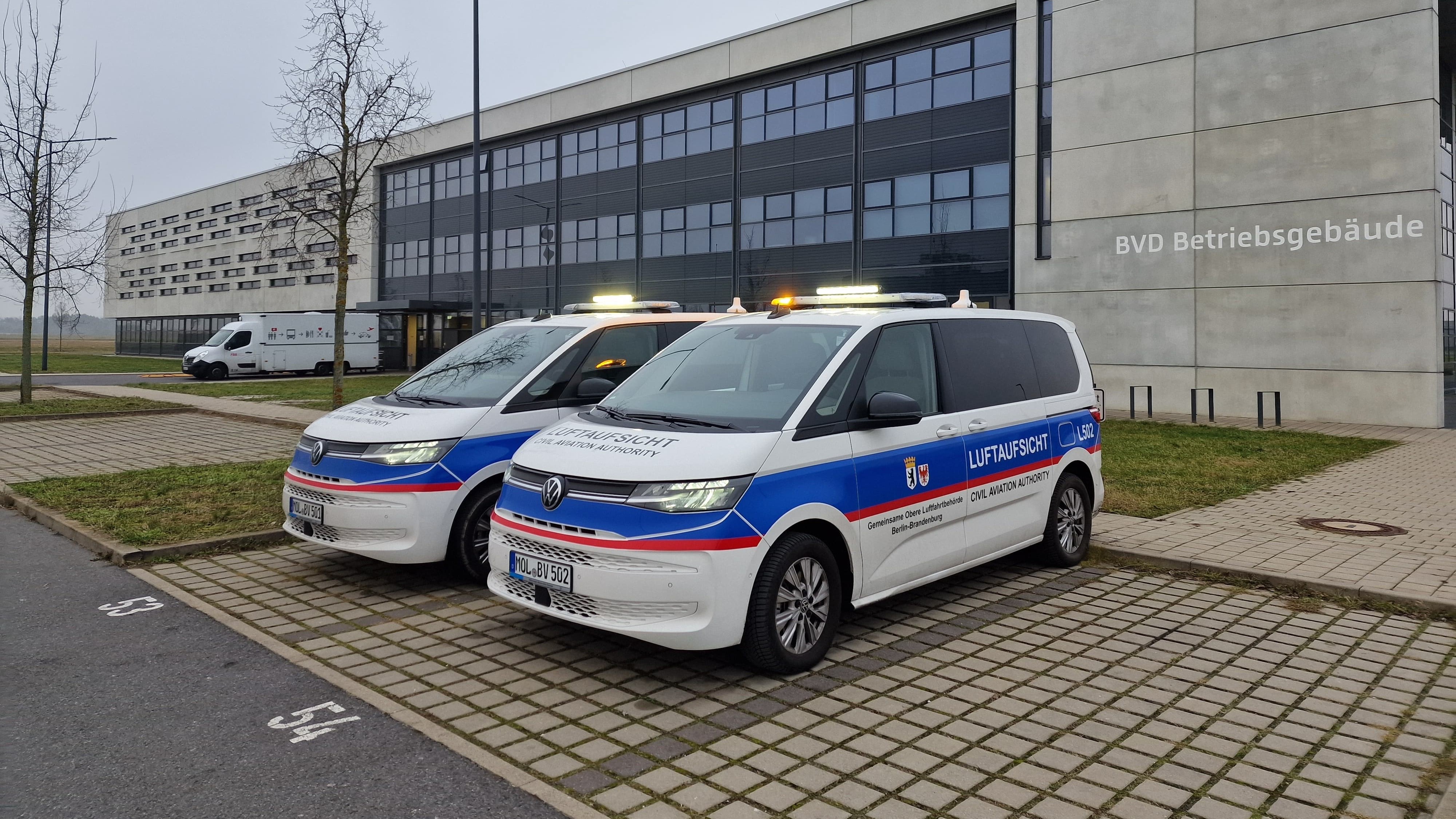 zwei Dienstfahrzeuge der Gemeinsamen Oberen Luftfahrtbehörde Berlin-Brandenburg auf dem Betriebsgelände des Flughafen BER.