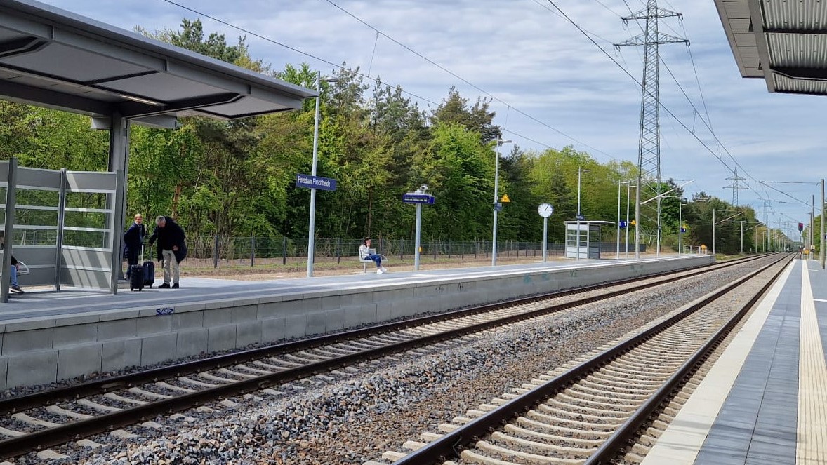 Gleisbett, Schotter, Bahnsteig mit Menschen in Potsdam-Pirschheide, Freileitungen