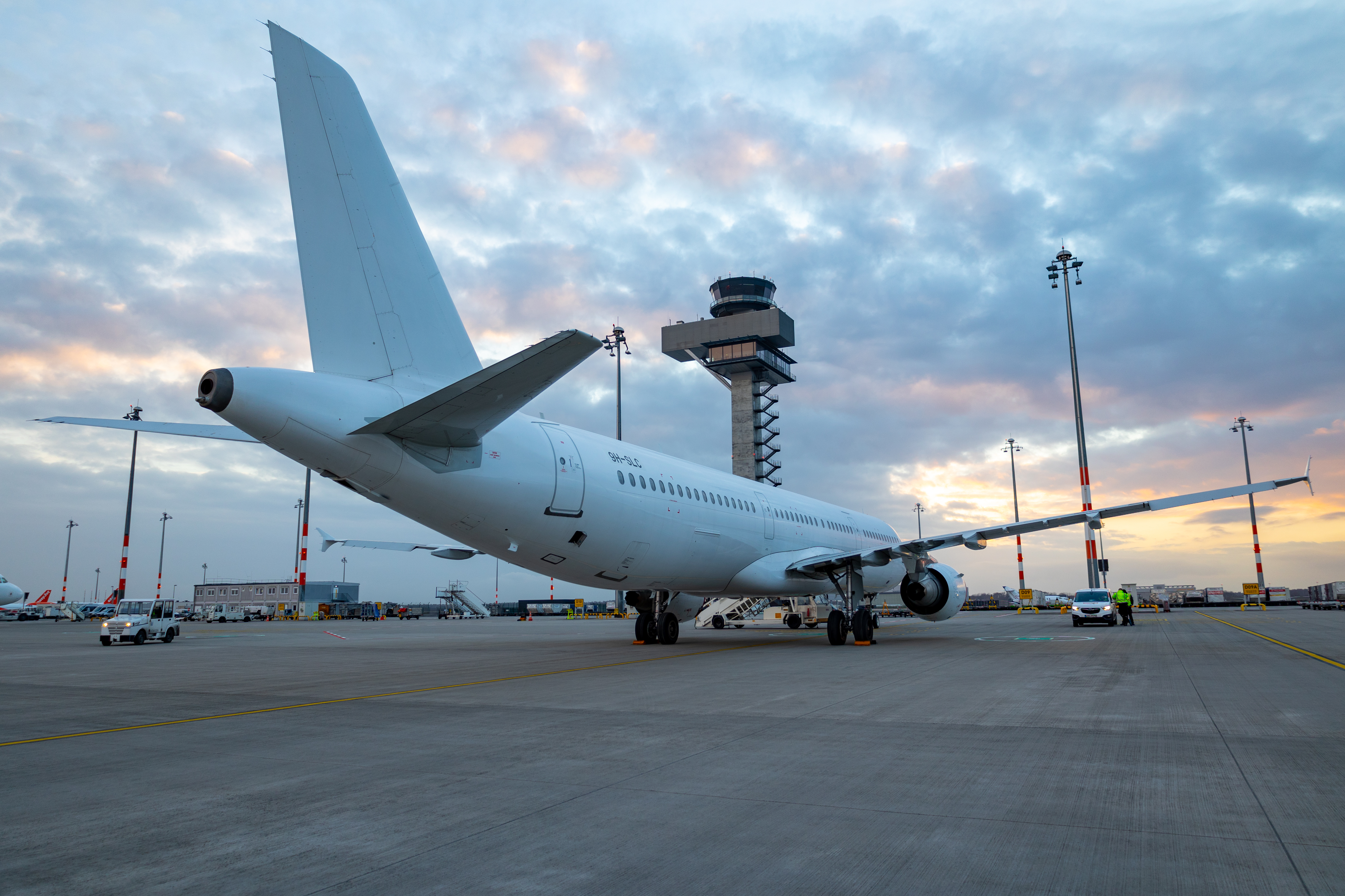 Passagierflugzeug steht auf dem Vorfeld des Flughafens vor dem Tower bei Sonnenuntergang