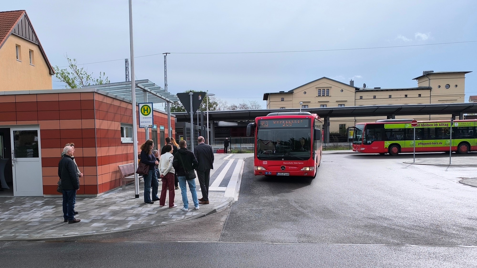 Menschen und zwei Busse am Bahnhofsvorplatz Eisenhüttenstadt, Haltestelle