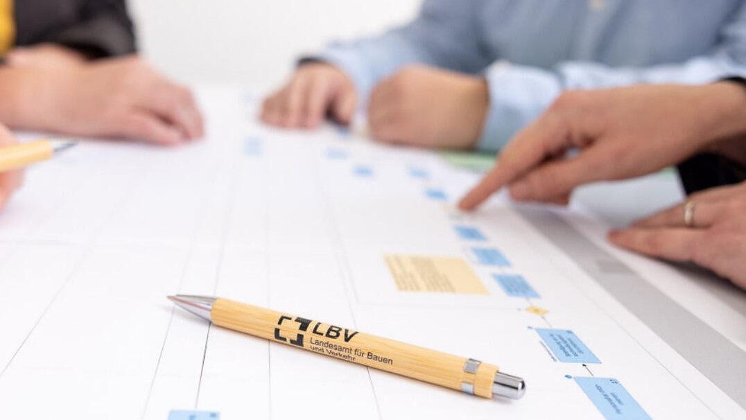 Kugelschreiber mit dem Logo des Landesamtes für Bauen und Verkehr liegt auf einem ausgedrucktem Geschäftsprozessmodell 