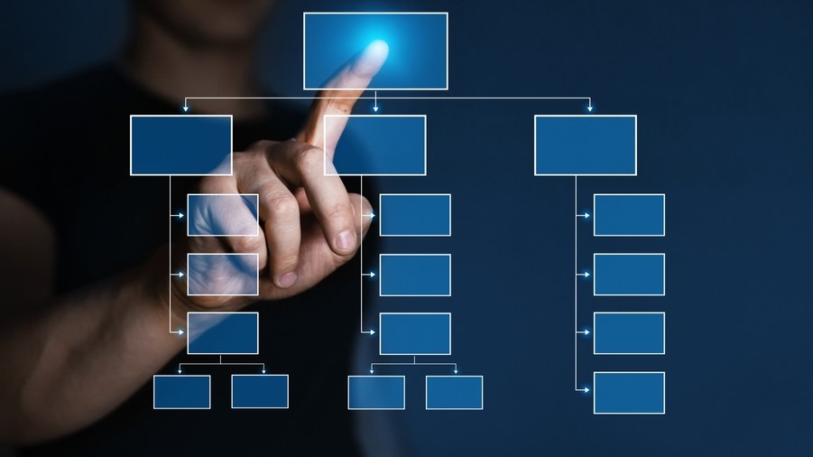 Eine Hand zeichnet mit einem Stift ein Organigramm auf eine Glasscheibe