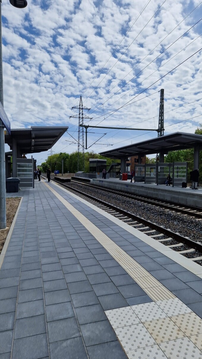 Schienen, Schotterbett, Blindenleitstreifen am Bahnsteig, Oberleitung