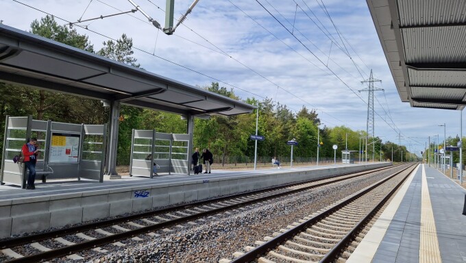 zwei Gleise, Schotterbett, Oberleitungen, wartende Menschen