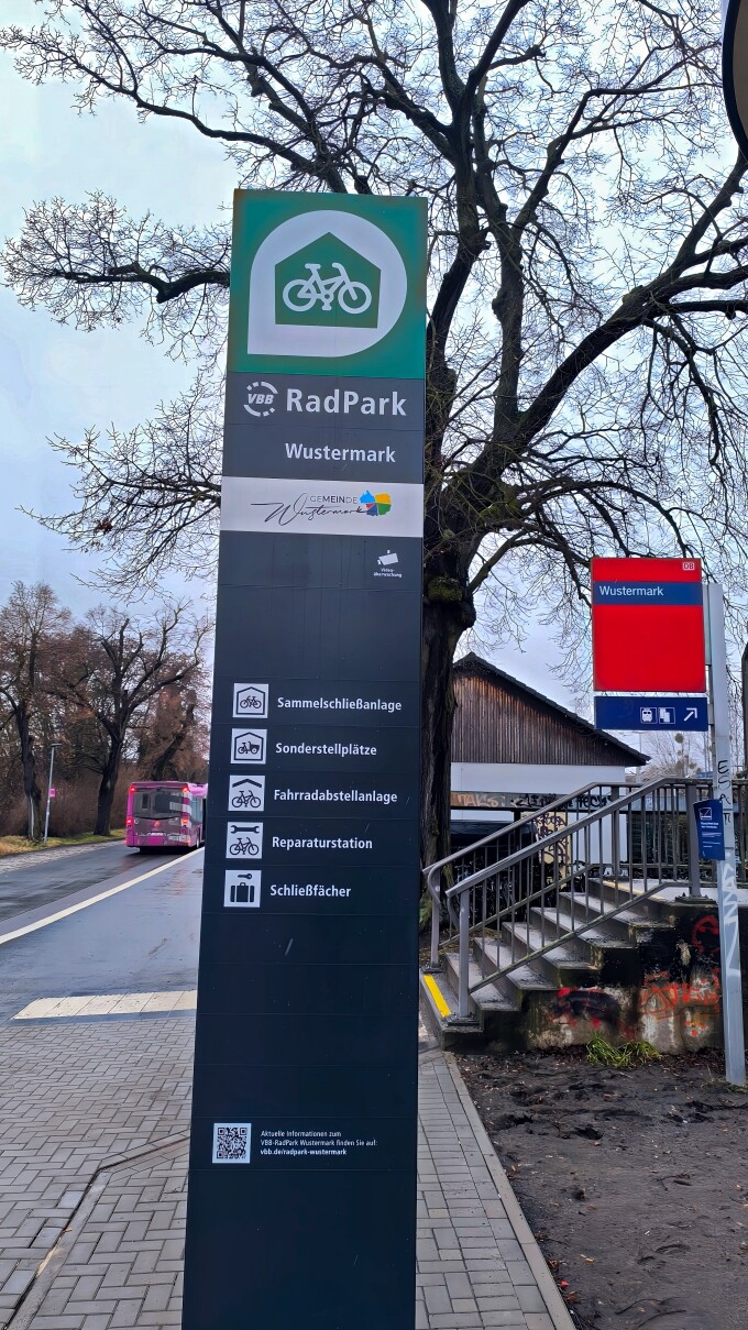Säule mit Informationen und Hinweisen, Logo des Radparks, rotes Schild mit Übergang zum Bahnsteig
