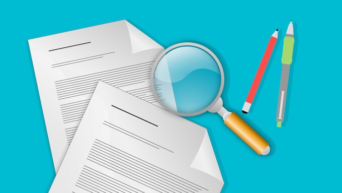 zwei Blatt Papier mit einer Lupe und zwei Stiften auf blauem Untergrund