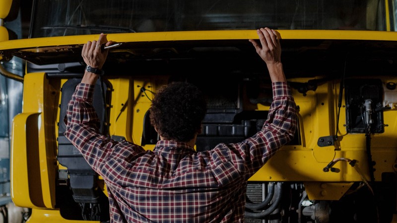 Mann vor geöffneter Motorhaube eines Lkw